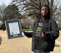 Black male holding his self advocate of the year award